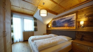 Ein Schlafzimmer mit Holzwänden, einem Bett, einem Gemälde und einem Nachttisch.