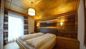 A wooden cabin-style bedroom with two beds, a large window with curtains, a painting on the wall, and a ceiling light. - Apartment 'Agriturismo Grones' with Mountain View, Shared Terrace and Wi-Fi (San Martin de Tor)
