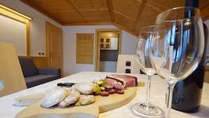 A wooden dining table with a cheese board, wine glasses, and a bottle. - Apartment 'Agriturismo Grones' with Mountain View, Shared Terrace and Wi-Fi (San Martin de Tor)