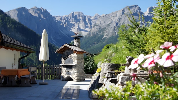 A stone-built outdoor seating area with a view of mountains. - Apartment 'Agriturismo Grones' with Mountain View, Shared Terrace and Wi-Fi (San Martin de Tor)
