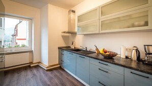 Een moderne keuken met een raam, een radiator en een schaal fruit op het aanrecht.