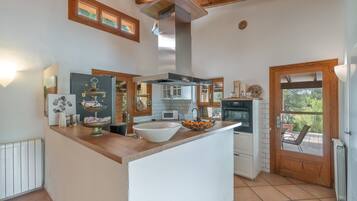 A kitchen with a central island, wooden cabinets, a built-in oven, and a view through the door.