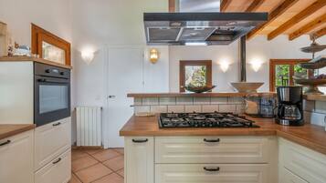 Una cocina con estufa a gas, horno y cafetera.