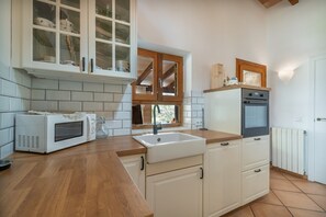 A kitchen with white cabinets, a microwave, a sink, and a wooden countertop. - Country House 'Bellpuig' with Mountain View, Wi-Fi and Air Conditioning (Artà)