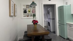 A kitchen with a dining table, a hanging light fixture, a clock, and a washing machine. - Modern 3BR Apartment Near NYC & Cruise Port (Bayonne)