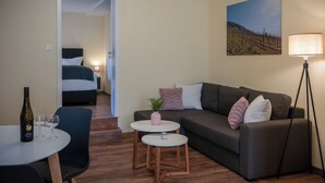 Moderni hotellihuone, jossa on sänky, sohva, pieni pöytä ja lattiavalaisin.