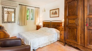 A bedroom with a bed, a wooden wardrobe, a mirror, and a window with curtains.