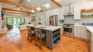 A spacious kitchen with wooden beams, a central island, and modern appliances. - MORNING LIGHT (Swanton)