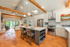 A spacious kitchen with wooden beams, a central island, and modern appliances. - MORNING LIGHT (Swanton)