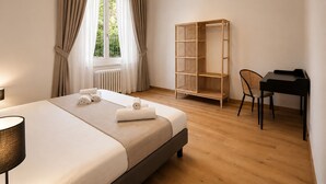 A hotel room with a bed, a desk, a chair, a wardrobe, and a window with curtains. - Modern Terrace Retreat (Florence)