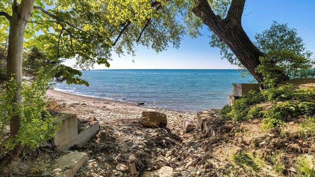 Une plage bordée d’un rivage rocheux, avec des arbres et une vue dégagée sur la mer.