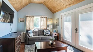 Un salon chaleureux avec un plafond en bois, un canapé, une table basse et un téléviseur.
