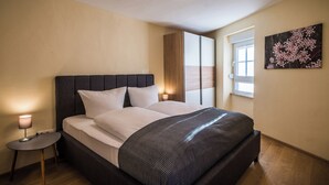 Quarto com cama, abajur e janela com persianas.