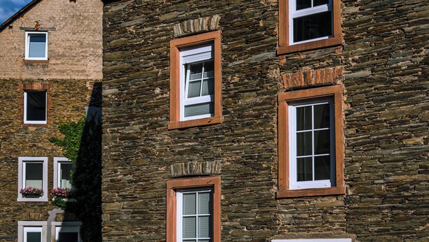 Um edifício de pedra com várias janelas, uma porta e uma placa indicando um restaurante.