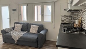 A modern kitchen with a gas stove, a sink, and a window overlooking the street.