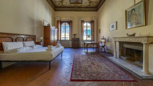 Una habitación con una cama, chimenea, una mesa y un ventanal grande.