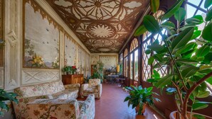 Amplia habitación con techo alto, sofás con estampado floral, plantas en macetas y un comedor.