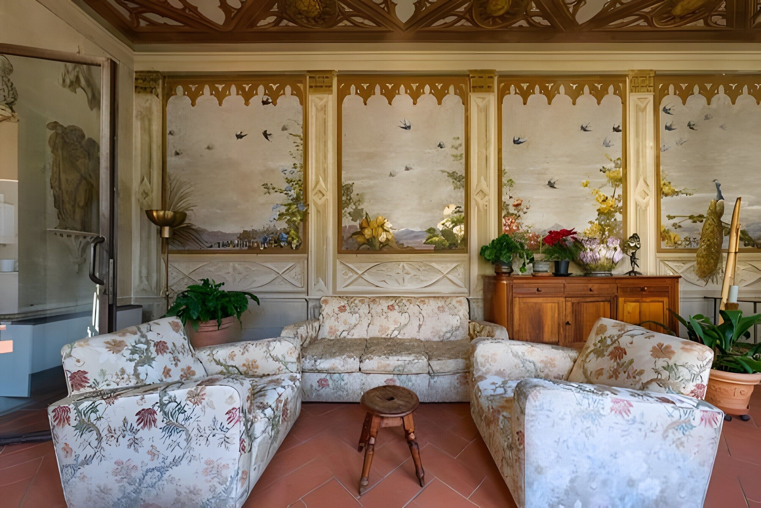 A room with a floral sofa, a wooden cabinet, and a decorative ceiling.