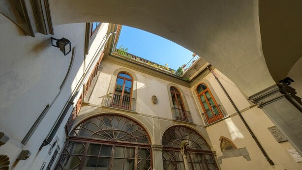 Un edificio con ventanas de arco y balcones, cielo despejado y un elemento arquitectónico curvo.