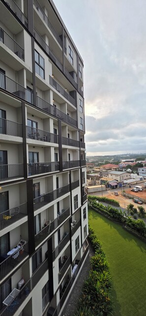 Un edificio de varios pisos con balcones, un césped verde y vistas del entorno.