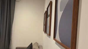 Una habitación moderna con sofá, aire acondicionado instalado en la pared y cuadros enmarcados.