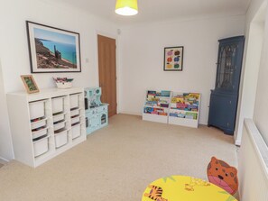 Ein Kinderzimmer mit Stauraumeinheiten, einem Bücherregal, einem gerahmten Bild und einem Schrank.