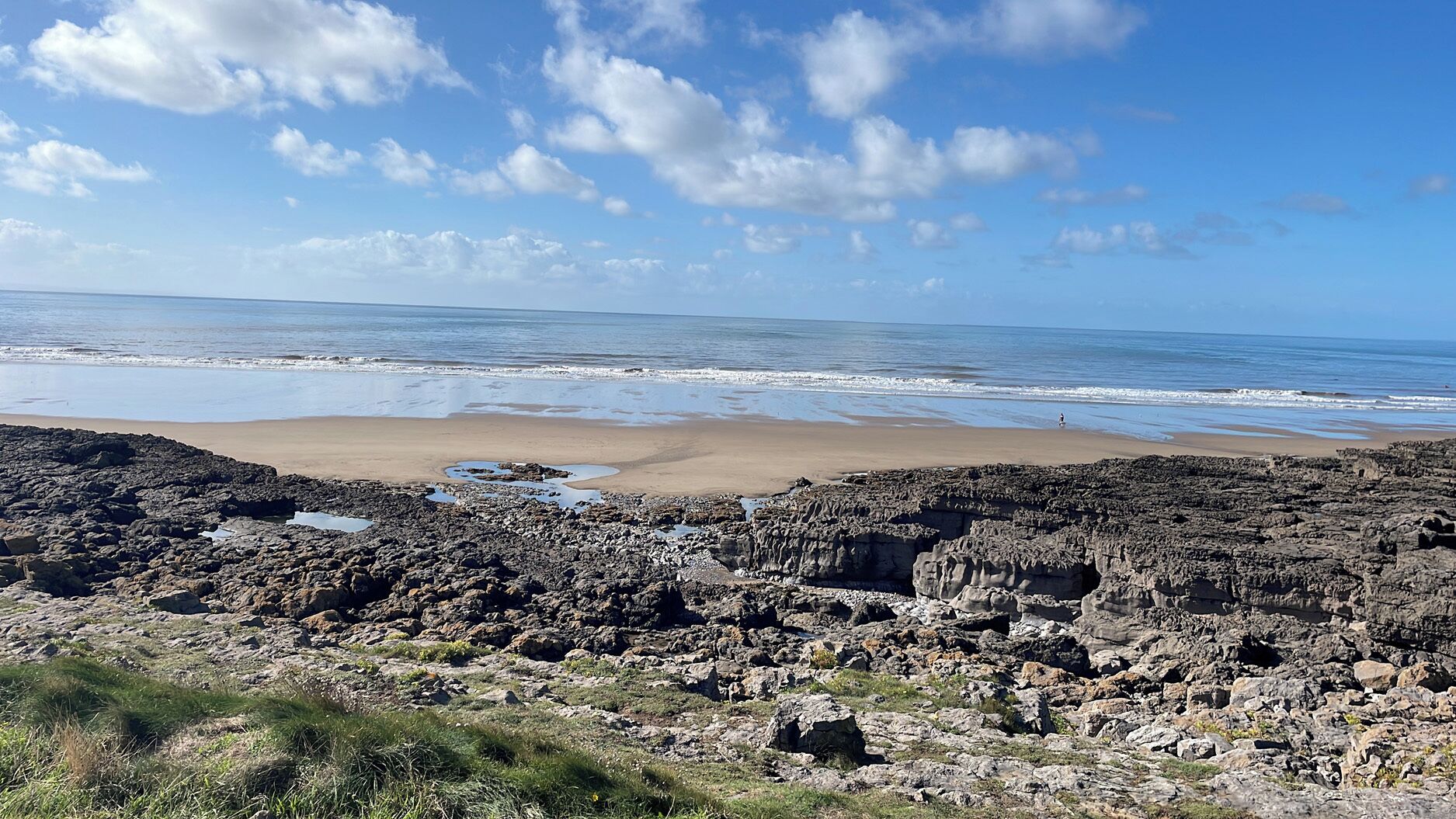 A rocky beach with waves, clear sky, and no visible buildings.