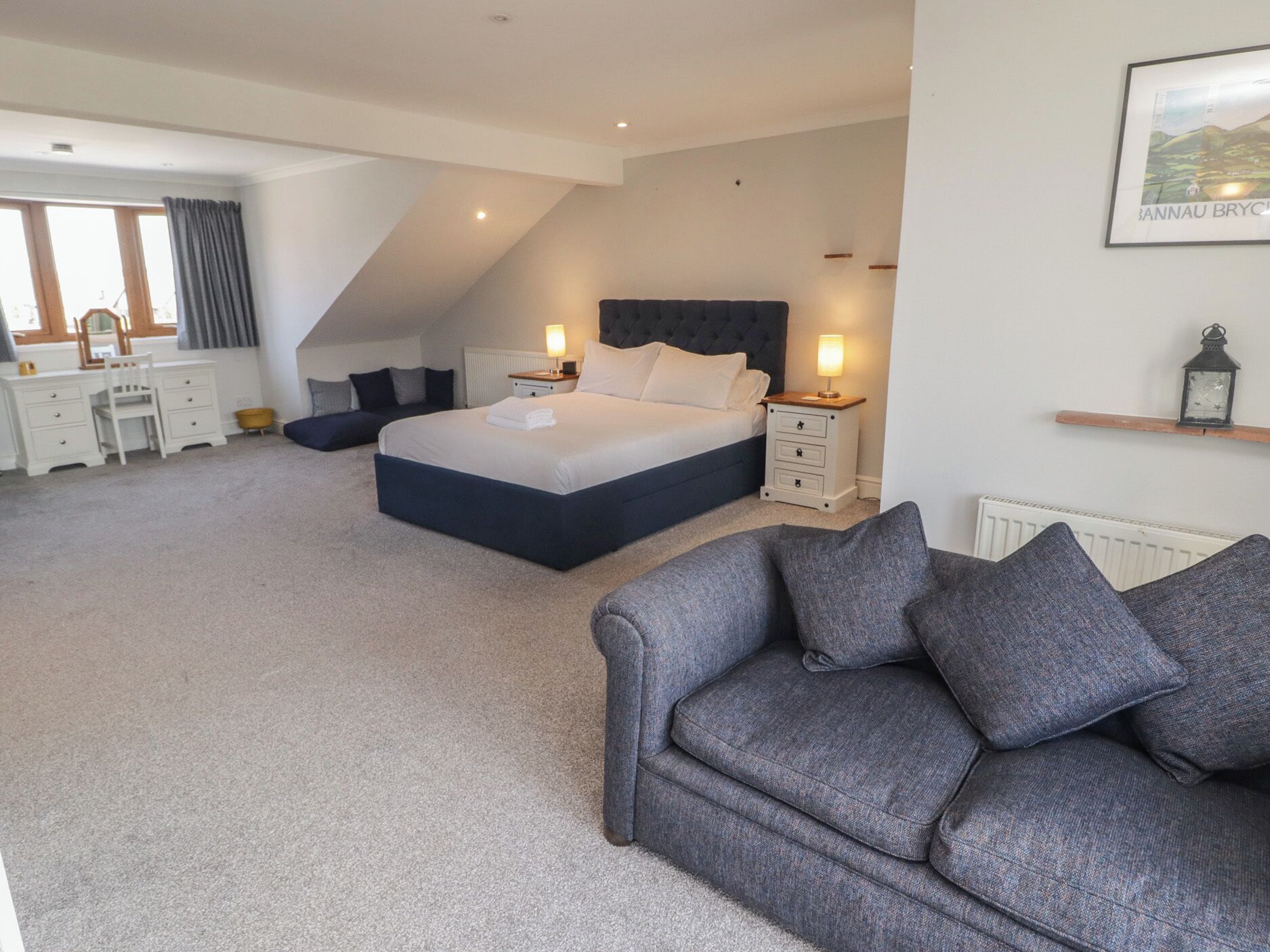 A bedroom with a large bed, bedside tables, a desk, and a chair.