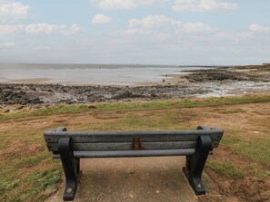 Eine Bank mit Blick auf einen felsigen Strand und das Meer.