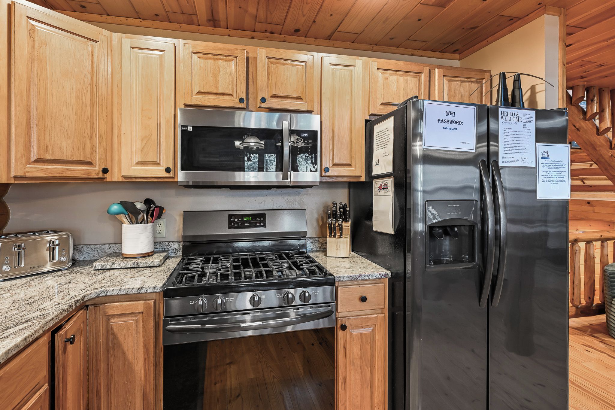 A kitchen with wooden cabinets, a stainless steel refrigerator, a microwave, a stove, and a coffee maker.