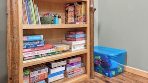 Une bibliothèque en bois remplie de divers jeux de société et casse-têtes.