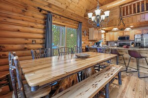 A wooden interior with a dining table, chairs, and a kitchen area.