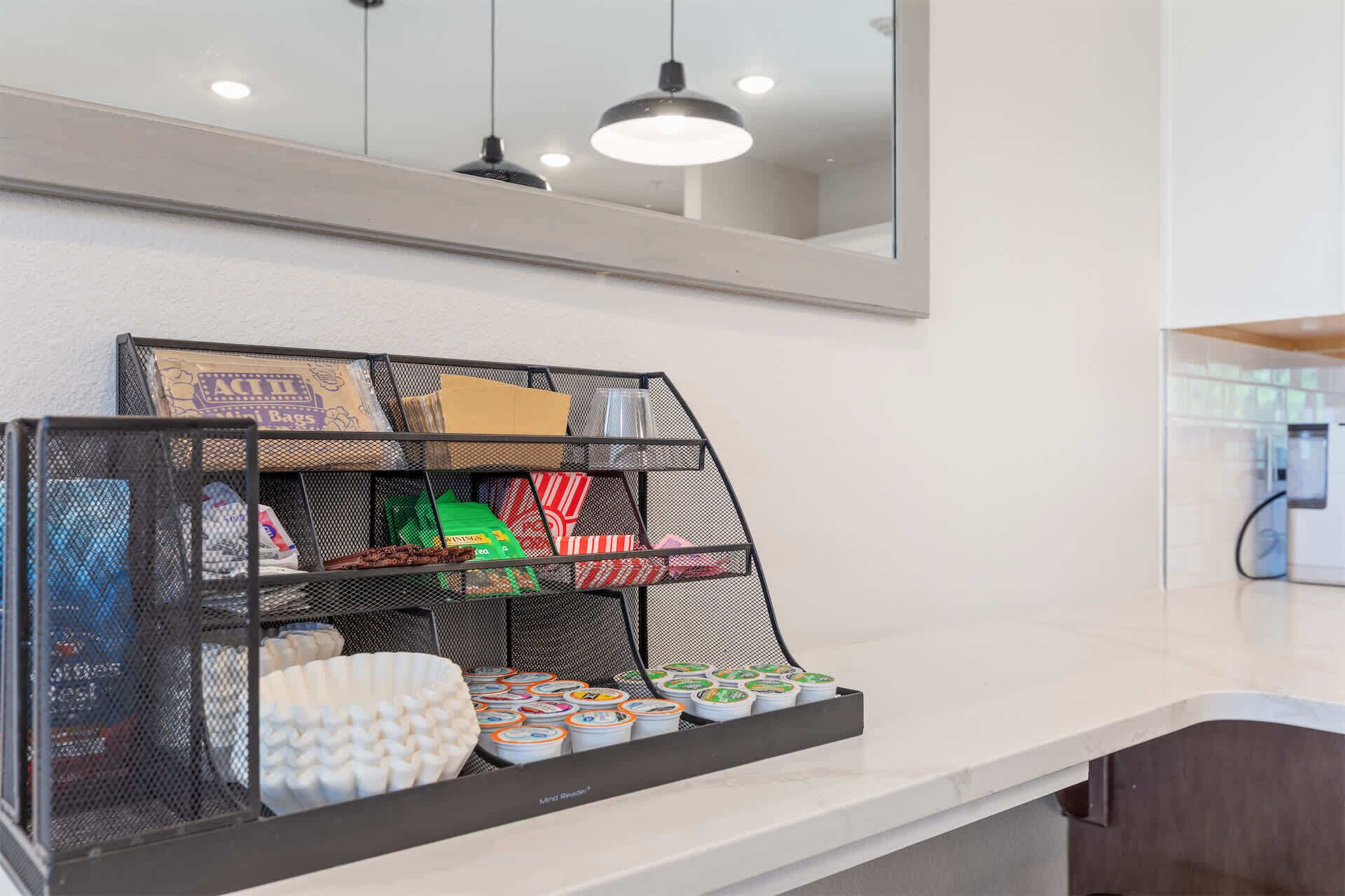 A kitchen counter with a black metal rack holding various items like tea bags and containers.