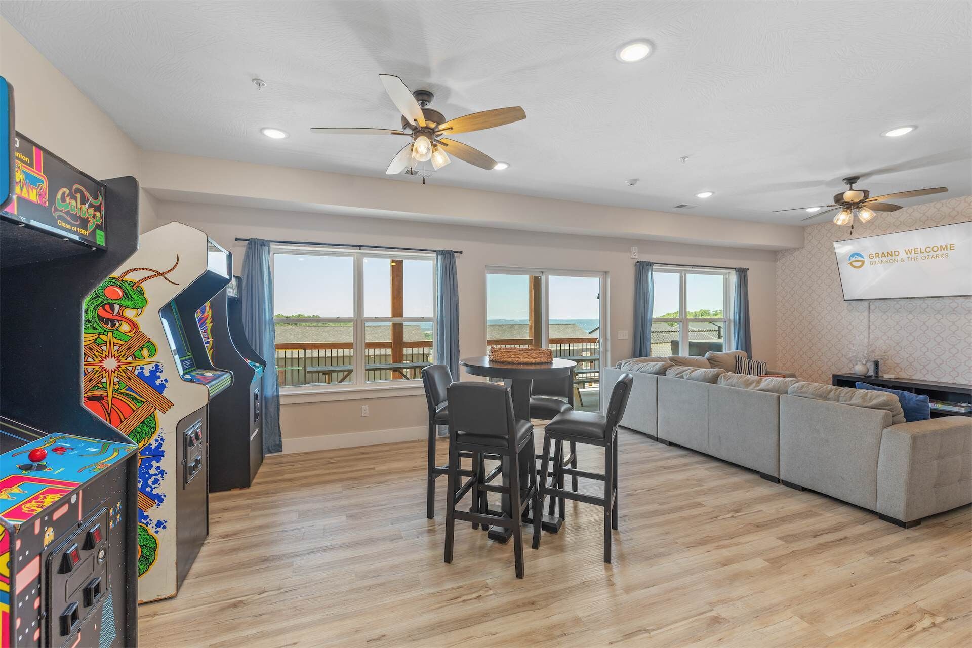 A spacious room with a dining area, a sofa, and arcade games.