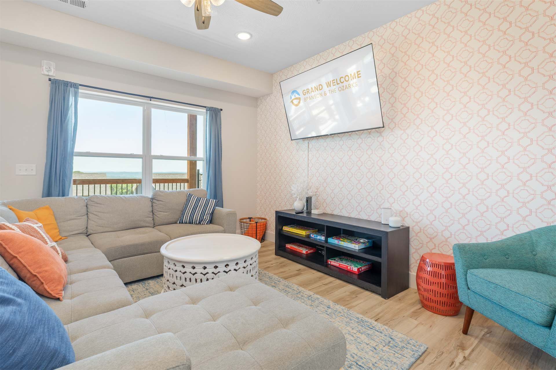Un salon comprenant un canapé, un pouf et un écran de télévision diffusant l’émission « Grand Welcome Branson & The Ozarks ».