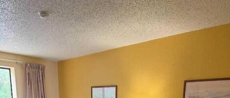 Habitación de hotel con dos camas, una mesita de noche con lámparas, una ventana con cortinas y un cuadro en la pared.