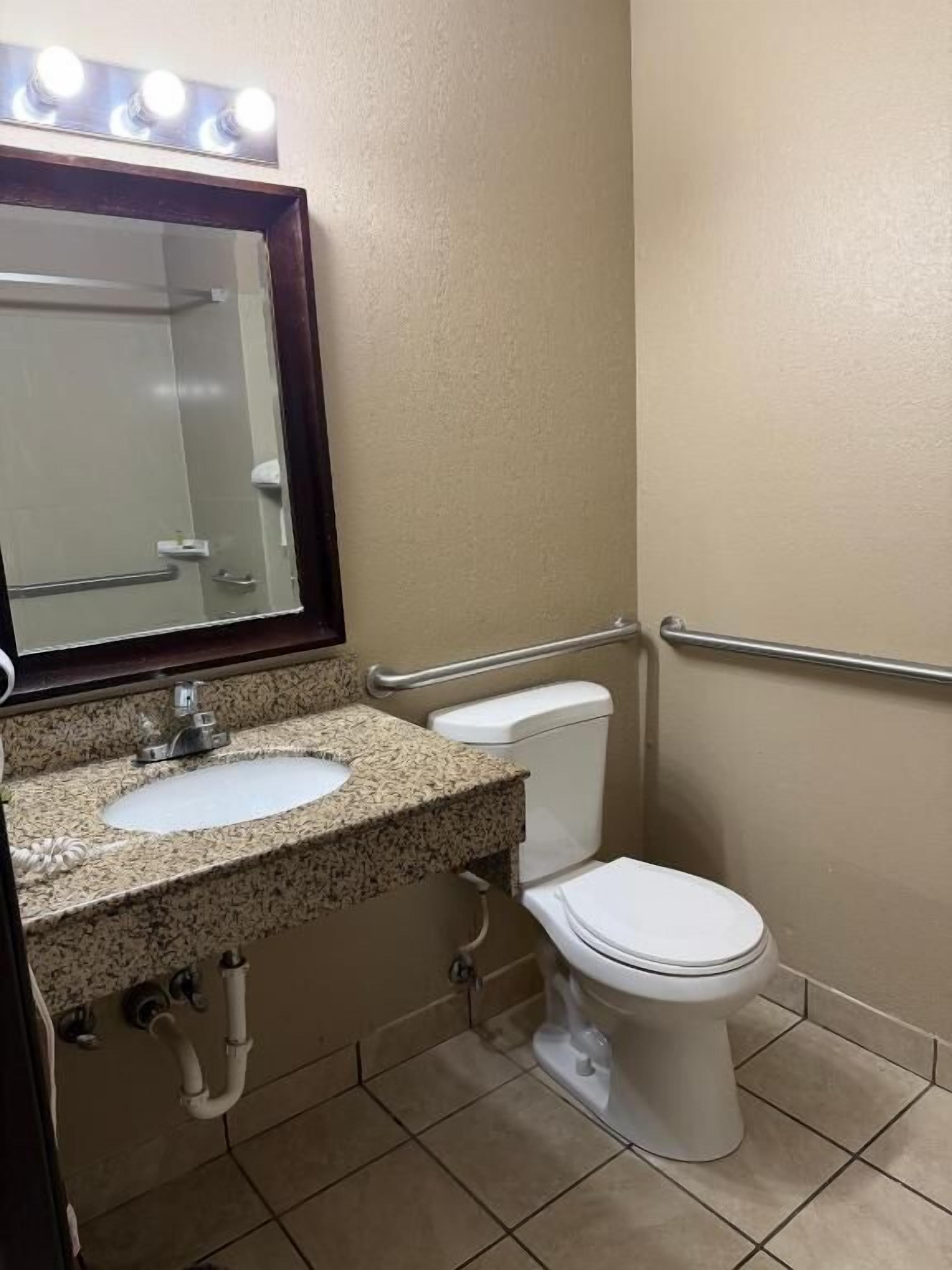 Un baño con lavamanos, espejo e inodoro.