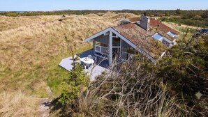A modern house with a sloped roof, large windows, and a patio area. - 4 Star Holiday Home in Saltum (Saltum)