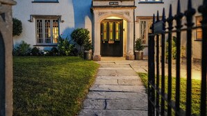 A stone pathway leading to a building with a black door and a sign above it. - Bath House - Country Luxury on the Somerset Levels (Aller)