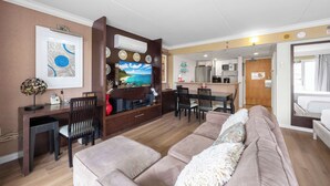 A living room with a sofa, a TV, a desk, and a dining area. - @ Marbella Lane - Iconic Waikiki City View Getaway (Honolulu)