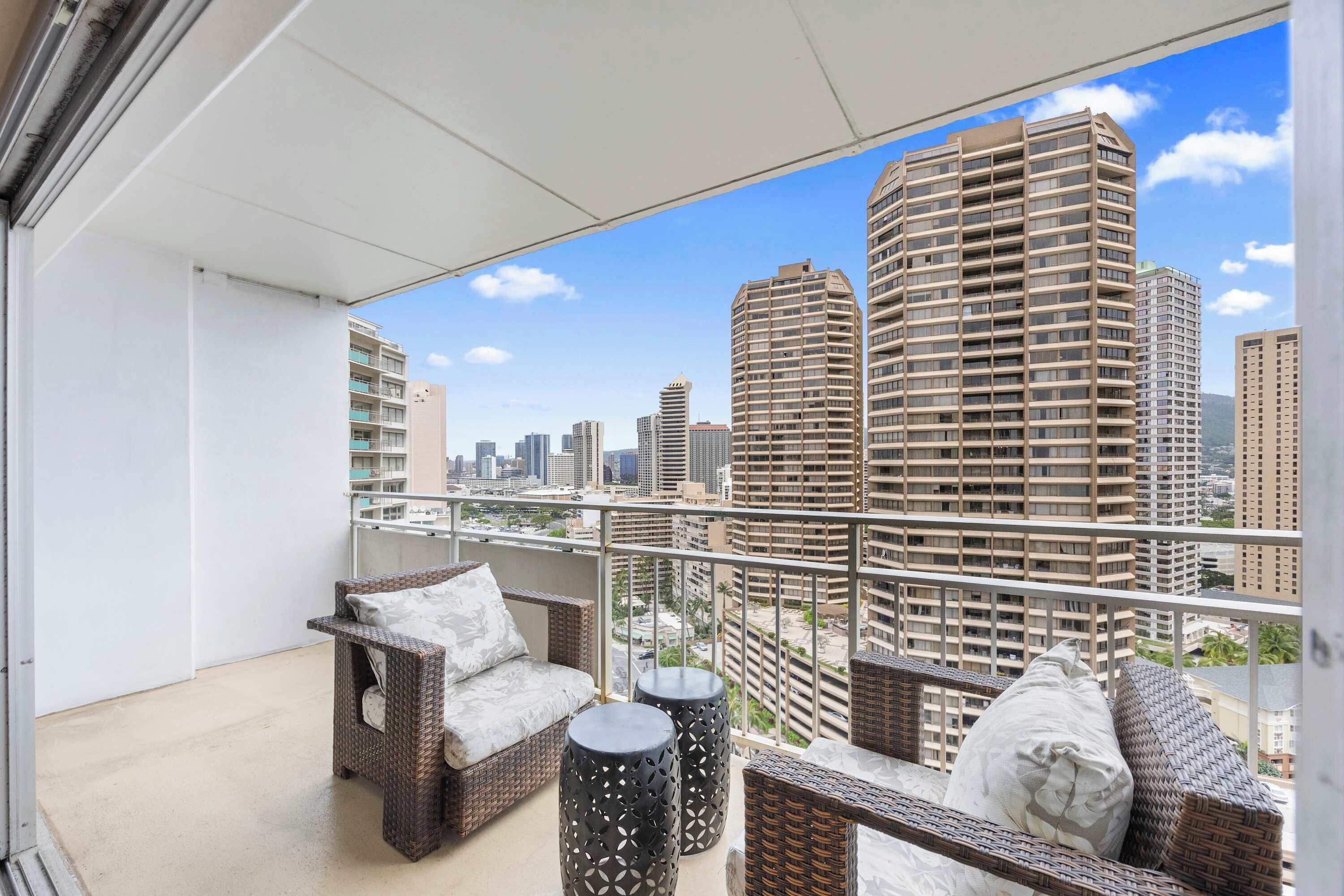 Ein Balkon mit Korbmöbeln und Blick auf die Stadt.