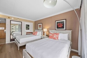 Ein Hotelzimmer mit zwei Betten, einem Nachttisch mit Lampe, einem großen Spiegel und einer Tür, die auf einen Balkon führt.
