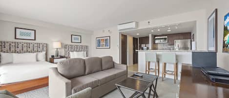 Une chambre d’hôtel moderne équipée d’un lit, d’un canapé, d’une table basse et d’une kitchenette.
