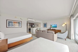 A hotel room with a bed, sofa, TV, and kitchenette.