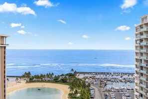 Vista costera con playa, puerto deportivo y edificios altos.