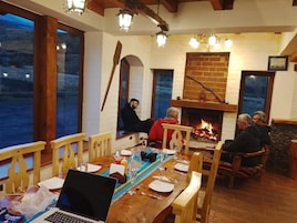 Un comedor con muebles de madera, chimenea y vistas amplias por las ventanas.