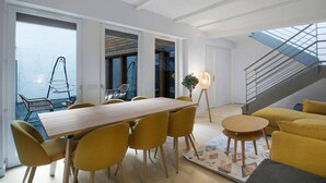 Ein modernes Interieur mit Essbereich, gelben Stühlen, einer Couch und einer Treppe.