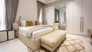 Un dormitorio moderno con una cama grande, un banco, un armario y un espejo.
