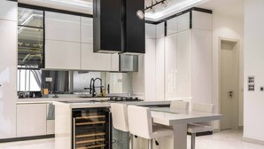 Una cocina moderna con muebles blancos, horno empotrado y una isla central con taburetes de bar.