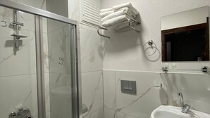 Une salle de bain avec une douche à parois de verre, des toilettes, un lavabo et un porte-serviettes.